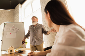 Male architect-engineer presents project of future house for young family. Man working in the office with documents, blueprint. First home, industrial, building concept. Moving to new live place.