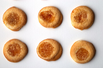 Six handmade cookies with apricot jam arranged in even rows on white background