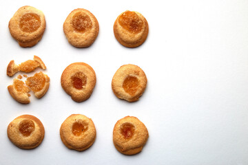 Nine handmade cookies with apricot jam arranged in even rows with free space for text. One in the central row is broken. on white background