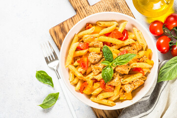 Pasta with chicken and vegetables at white table.