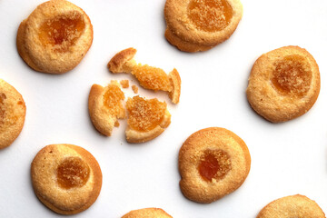 Six handmade cookies with apricot jam arranged in even rows from an angle. One in the center is broken. on white background