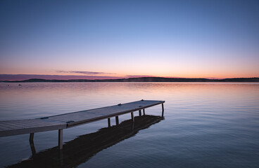 Small boat pier in cottage country. Calm lake with clear sky.