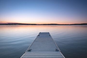 Fototapeta na wymiar Small boat pier in cottage country. Calm lake with clear sky.