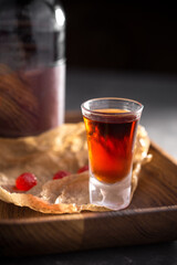 shot of alcohol on wooden tray with bottle on dark background