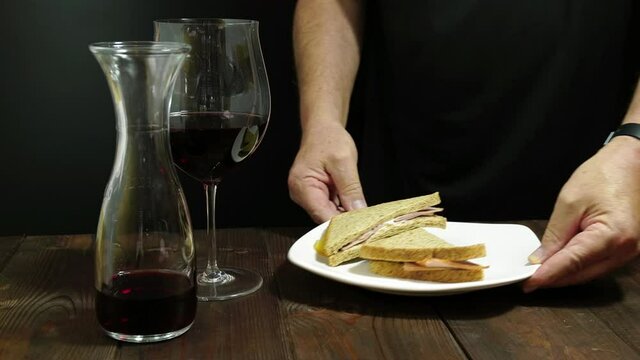 
Uomo mette sul tavolo il piatto con il panino
