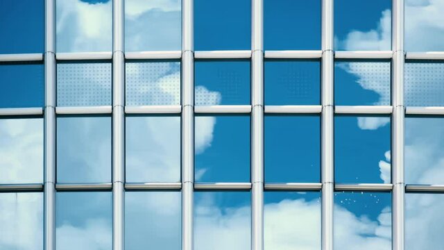 Time lapse of blue sky and clouds reflected in structural modular glass wall. 