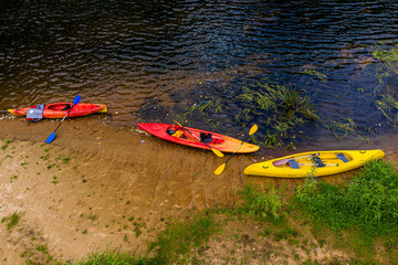 multicolored empty kayaks on the river bank, view from above
