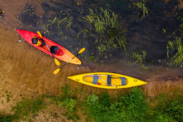multicolored empty kayaks on the river bank, view from above