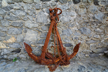 Ancore arrugginite appoggiate ad un muro in pietra (Camogli, Liguria, Italia)