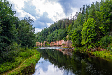Fototapeta premium landscape with sandstone cliffs on the river bank, fast flowing and clear river water, Kuku cliffs, Gauja river, Latvia