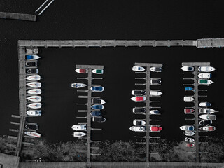 Aerial view of jetty with dark lake waters, Marina with colorful boats. Top down perspective. Drone shot. Background image.