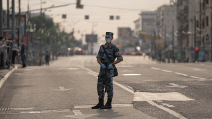 police in protective mask stands in the square in front of the parade rehearsal