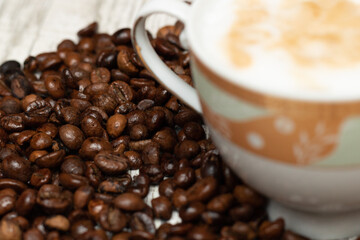 Small cup of cappuccino with coffee beans isolated on light background