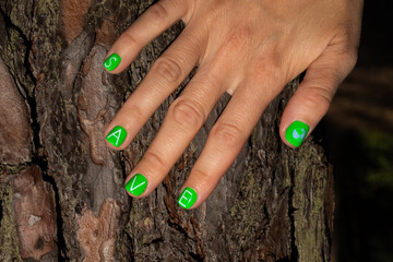 Hand with green manicure on the tree trunk. Save the planet concept