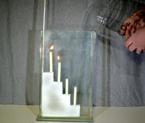 Carbondioxide (CO2) is poured from a large glass into another glass with 4 candles. Even if it seems that nothing is poured, the candles go out one by one starting from the bottom.