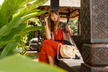Seductive stylish woman in bohemian summer clothes  posing in tropical luxury resort. Vacation  concept.
