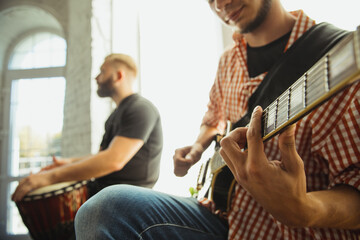 Close up hands playing. Musician band jamming together in art workplace with instruments. Caucasian men and women, musicians, playing and singing together. Concept of music, hobby, emotions, art