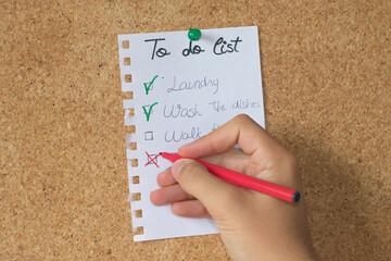 Hand putting a cross in a box. To do list on a cork board
