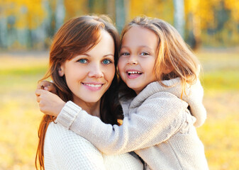 Autumn portrait of happy smiling mother with her daughter child in the park