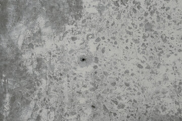 Old concrete wall with remnants of plaster for the backdrop. A hole drilled in the concrete in the center.
