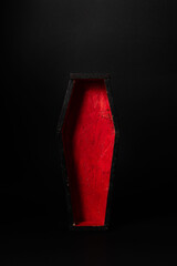 Miniature open black-red coffin on a black background. Festive halloween concept. A place for your product.