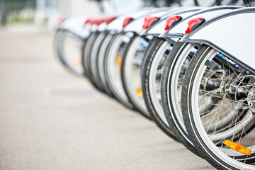 Row of rear wheels of parked bicycles at rental station. Close-up, selective focus
