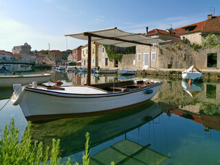 Fototapeta na wymiar Fisherman boat on the Canal in the harbor of Vrboska village, Hvar island, Croatia