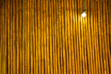 A hut had a wall made up of bamboo trunks that are straight and the same size. Those trunks were cut to equal length and applied with a coating, then fix it to the transverse wood with nails.