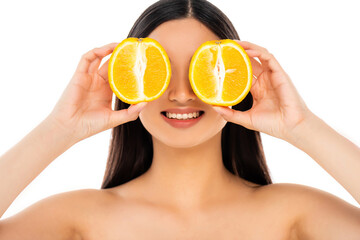 naked brunette woman covering eyes with halves of ripe orange isolated on white