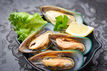 Fresh mussels on black bowl and ice with lemon and lettuce for cooked food - Seafood shellfish steamed mussels