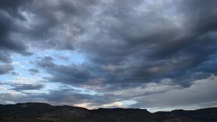 Dramatic afternoon sky with clouds over a silhouette of mountains on the horizon