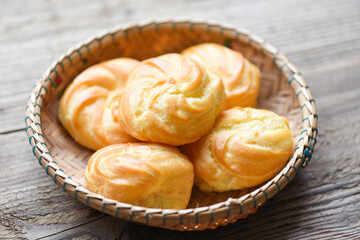 Cream puffs filled vanilla custard on basket wooden background - Delicious puff sweet treat