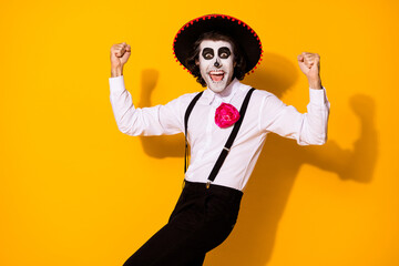 Photo portrait of cheerful crazy nice handsome funny mexican guy in traditional costume raising fists up isolated bright color yellow background
