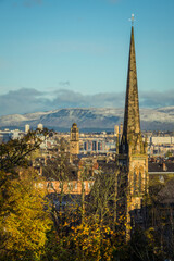 Church Spire in the Foreground of View Across Glasgow Scotland With Autumn Leaves and Snow Covered Hills