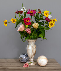 Still life with flowers balloons. A small bouquet of different flowers in a marble vase and marble balls. Vintage.