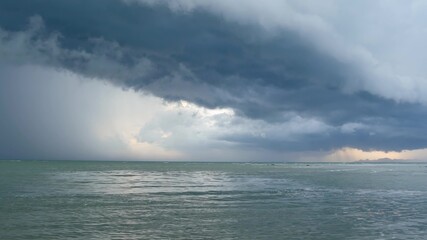 Obraz premium Waving blue sea, sandy shore of Koh Samui Island during wet rain season, Thailand. Hurricane and storm warning on exotic tropical ocean beach. Fast wind and ominous clouds. Danger typhoon thunderstorm
