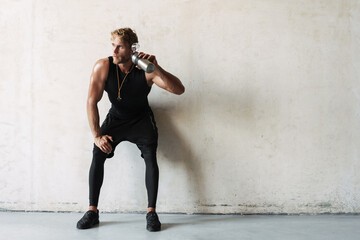 Attractive tired sportsman having a drink after workout