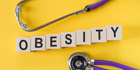 The word OBESITY, spelt with wooden letters on yellow background, medical concept