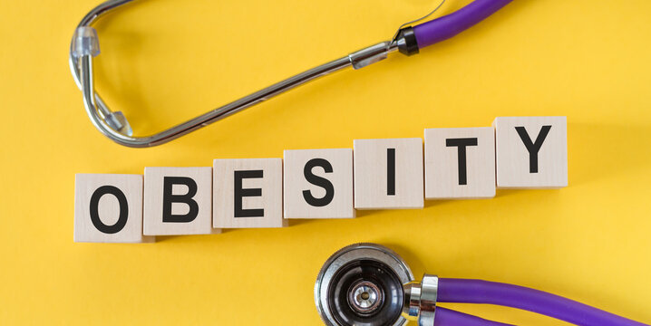The word OBESITY, spelt with wooden letters on yellow background, medical concept