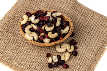 Cashews and cranberries. Mix of nuts and dried fruits in a basket on burlap isolated on a white background.