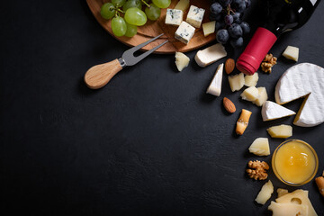Menu frame with different types of cheese, honey, grapes and wine on black background