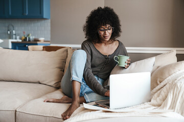 Image of woman drinking coffee while working with laptop