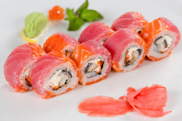 Суши красиво выложены дополнительными ингредиентами снятые на белом фоне
