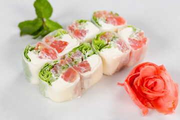 Суши красиво выложены дополнительными ингредиентами снятые на белом фоне