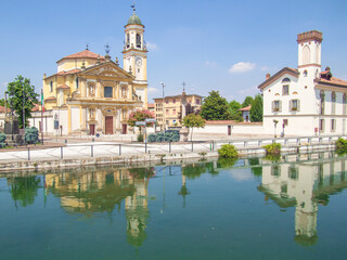 Fototapeta premium the historic center of gaggiano, in the province of Milan, reflected in the Naviglio Grande, an ancient navigable canal
