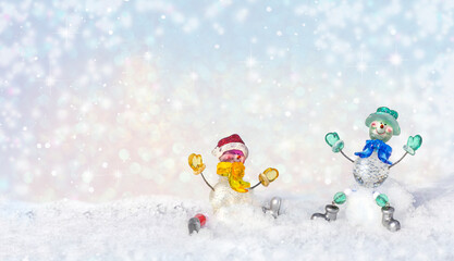 Funny snowmen carefree on snow in winter new year landscape. Beautiful bokeh circles Christmas snowy background, banner format, copy space.