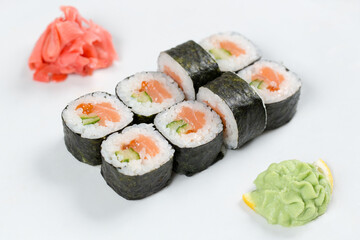 Суши красиво выложены дополнительными ингредиентами снятые на белом фоне