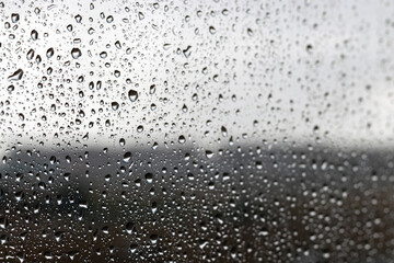 Drops of water on the glass against a blurred dark light gradient background on a rainy cloudy day. Selective focus