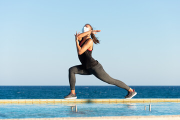 Young woman with protective surgical face mask performing yoga stretching exercises outdoor during covid-19 coronavirus pandemic