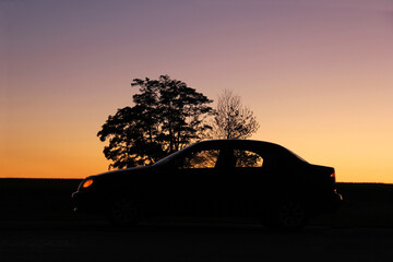 Car in the shade on the background of the sunset. Silhouette of the car. Wallpaper. Background